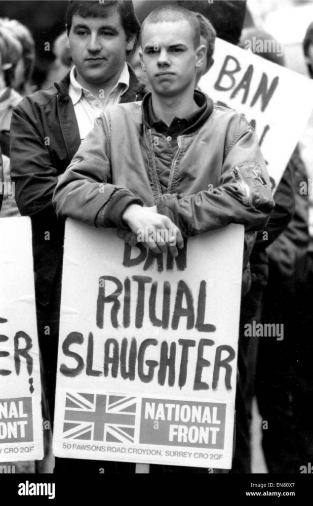 Skinhead member of National Front holding a sign that says Ban Ritual Slaughter